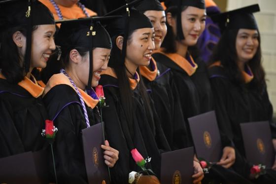 Photo of a group of international students in caps and gowns, at a Chatham University commencement ceremony