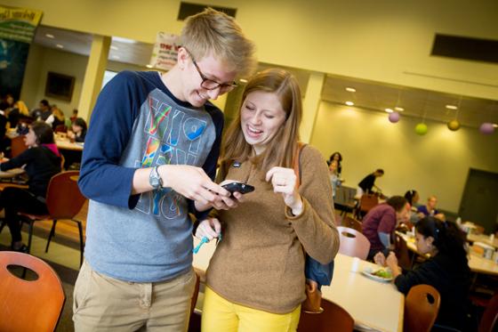 Photo of two Chatham University students smiling and looking at a phone together