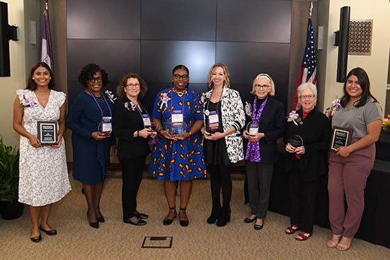 Photo of a group of alumni smiling and holding awards