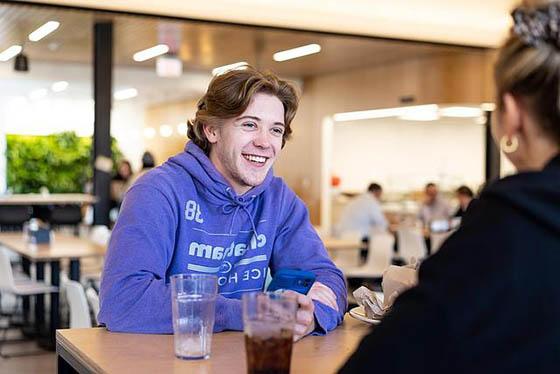 Photo of a student and a success coach speaking and laughing together on a bench